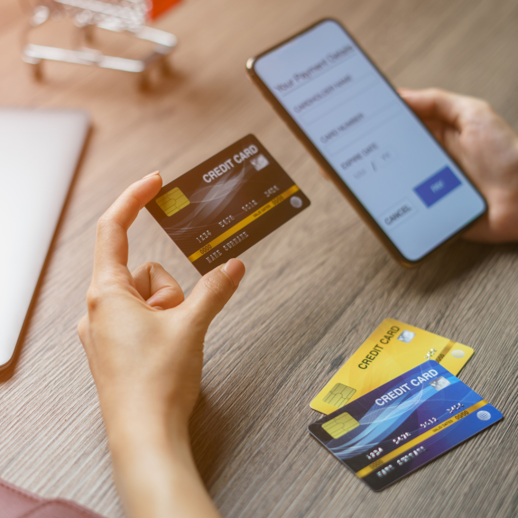 A person holds a credit card and a mobile phone